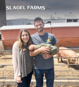 a man and a woman holding a baby in a pen showcasing slagel family farm