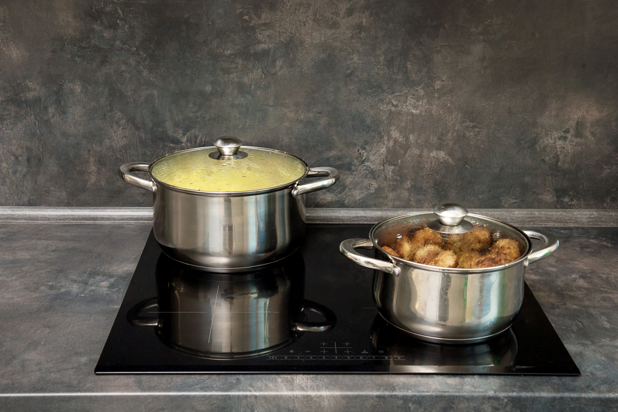 pots with cutlets and boiled potatoes on the induction stove.