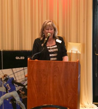 a woman standing at a podium in front of a microphone