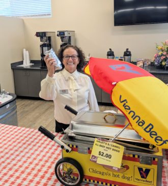 a woman holding up a cell phone in front of a vendor cart