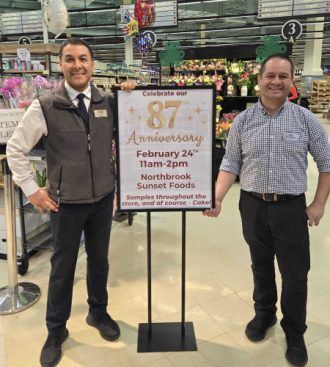 two men standing next to a sign in a store