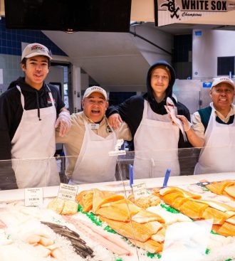 a group of people in aprons behind a seafood counter